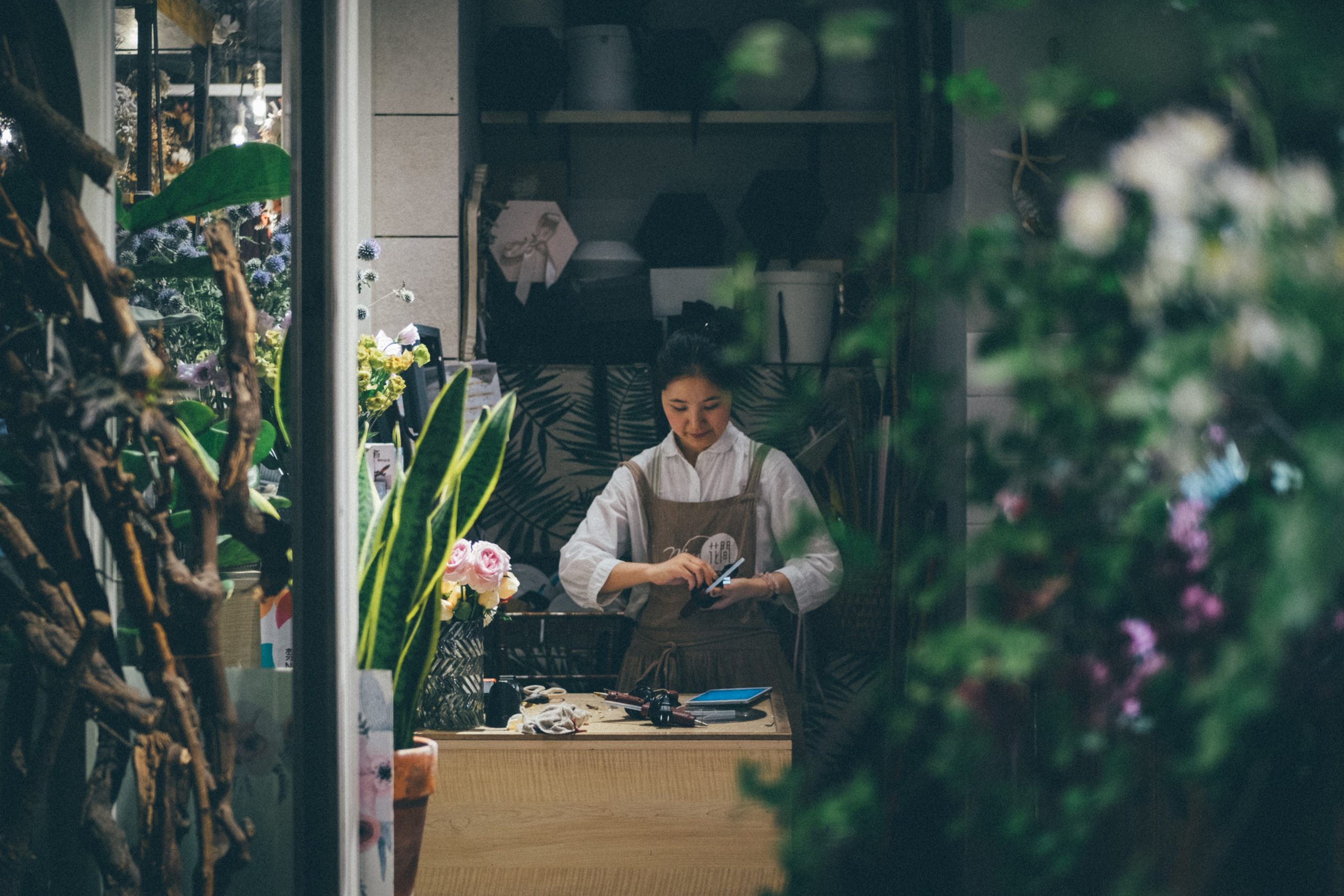 woman in flower shop standing beside a table