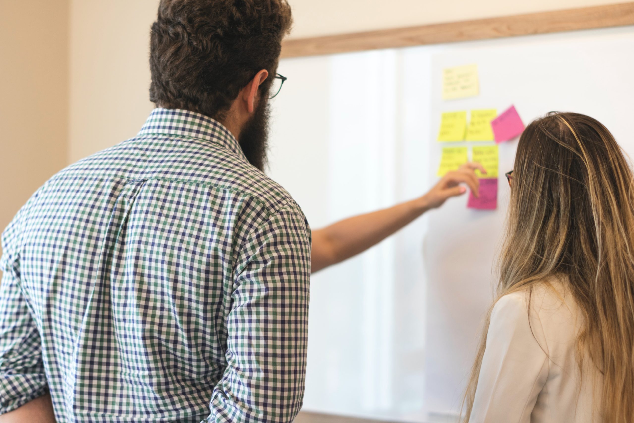 a professor looking over two students' work on a white board
